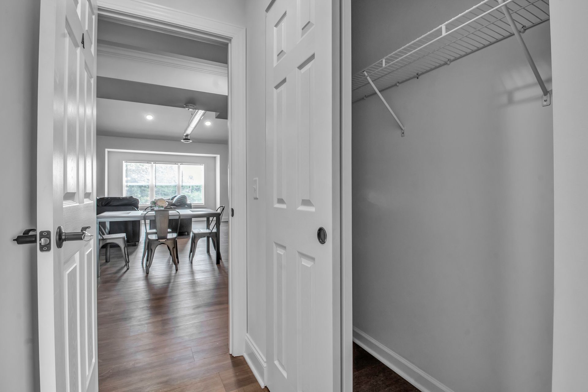 A hallway with a closet and a dining room in the background.