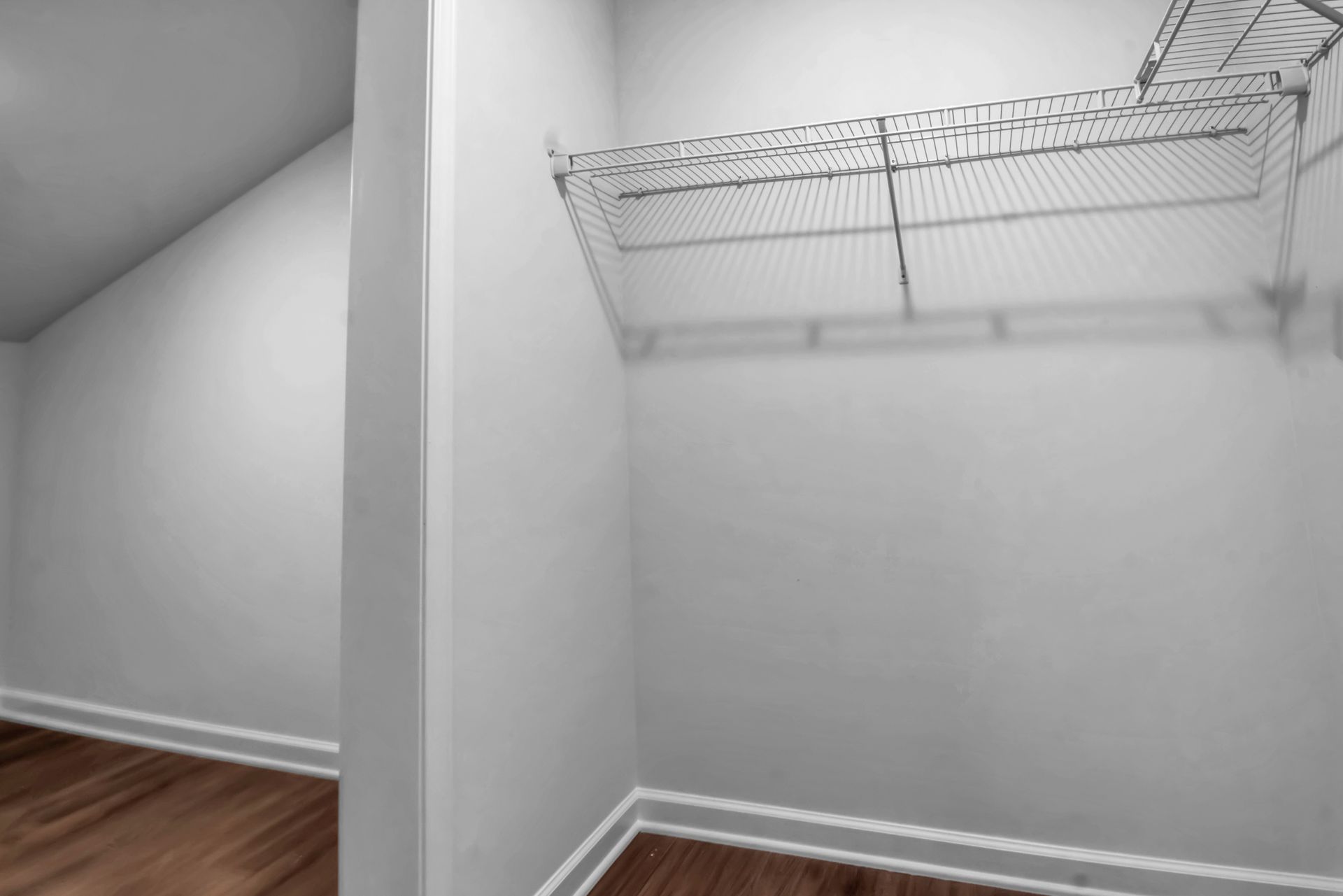 An empty walk in closet with wooden floors and white walls
