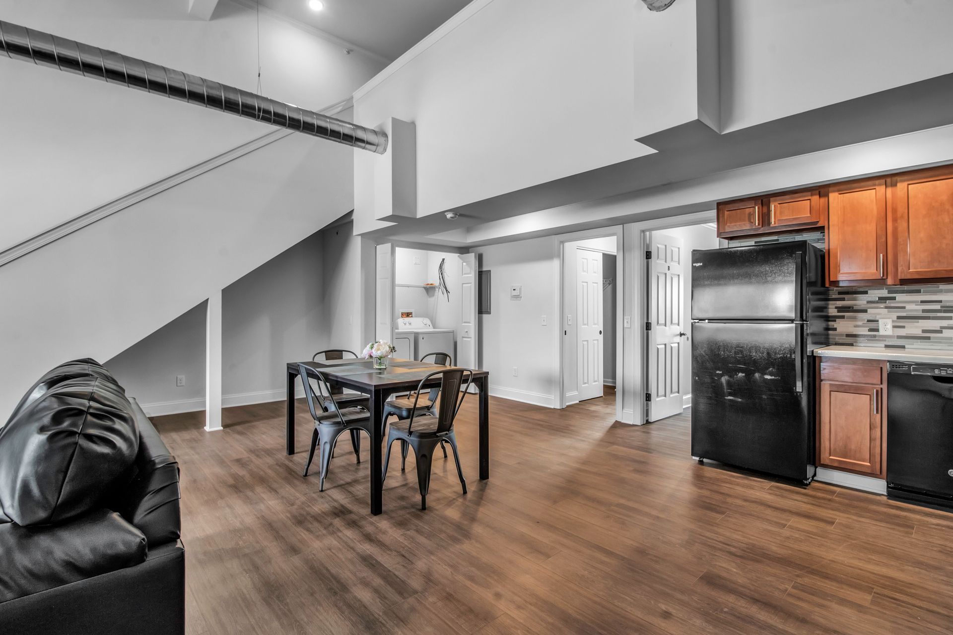 A living room with a couch , table , chairs and a refrigerator.