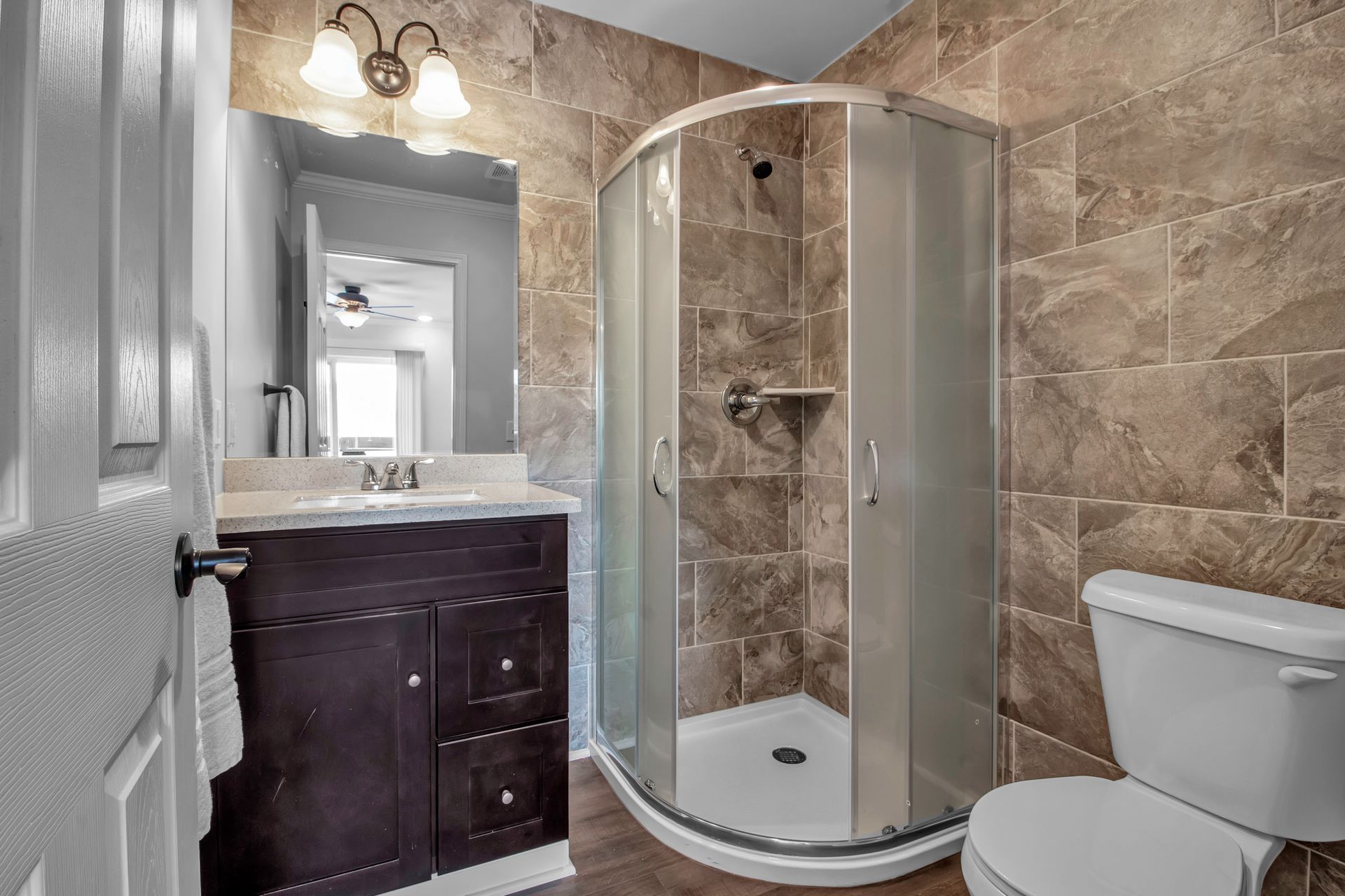 A bathroom with a toilet , sink , shower and mirror.