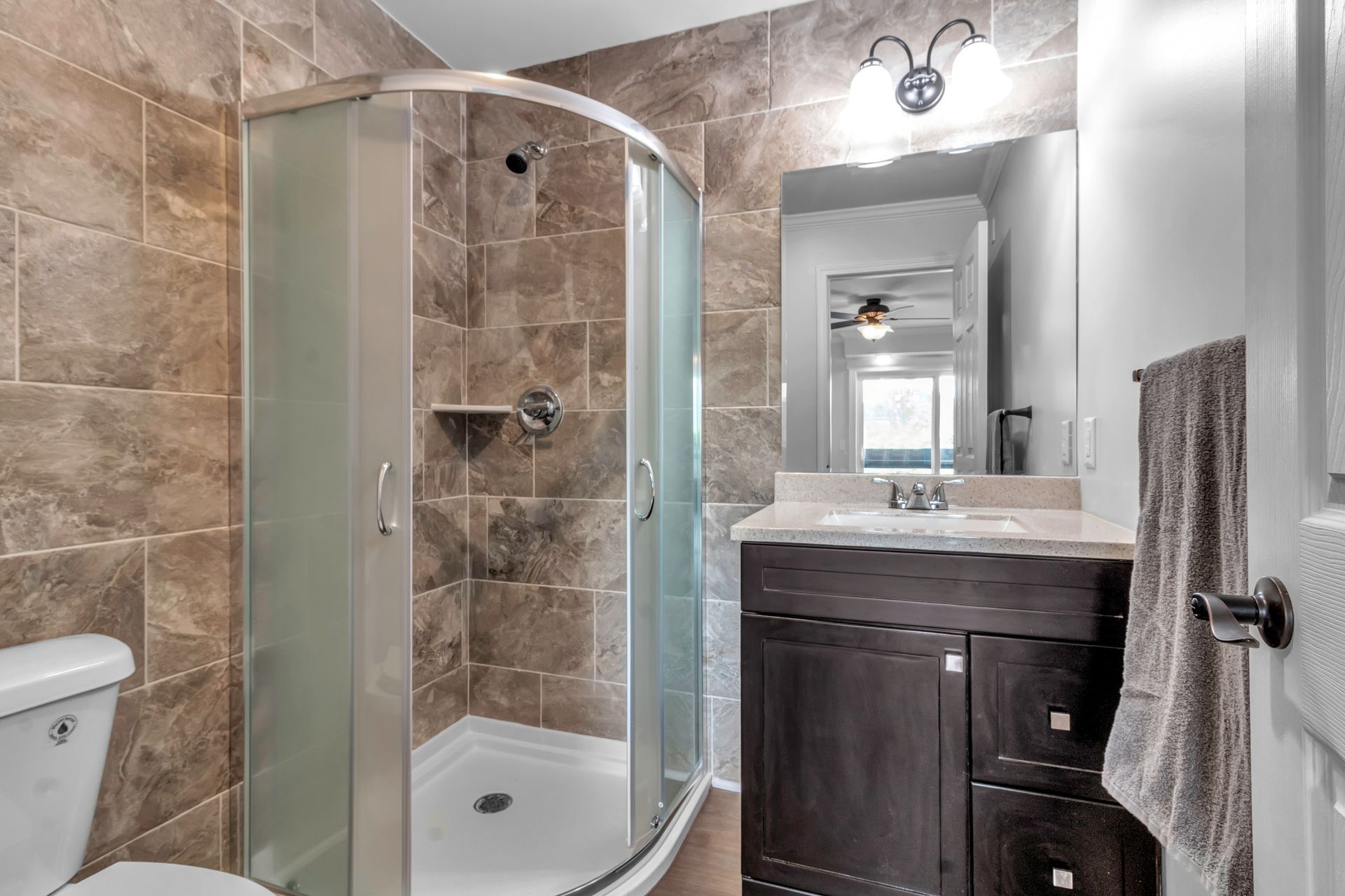 A bathroom with a toilet , sink , shower and mirror.