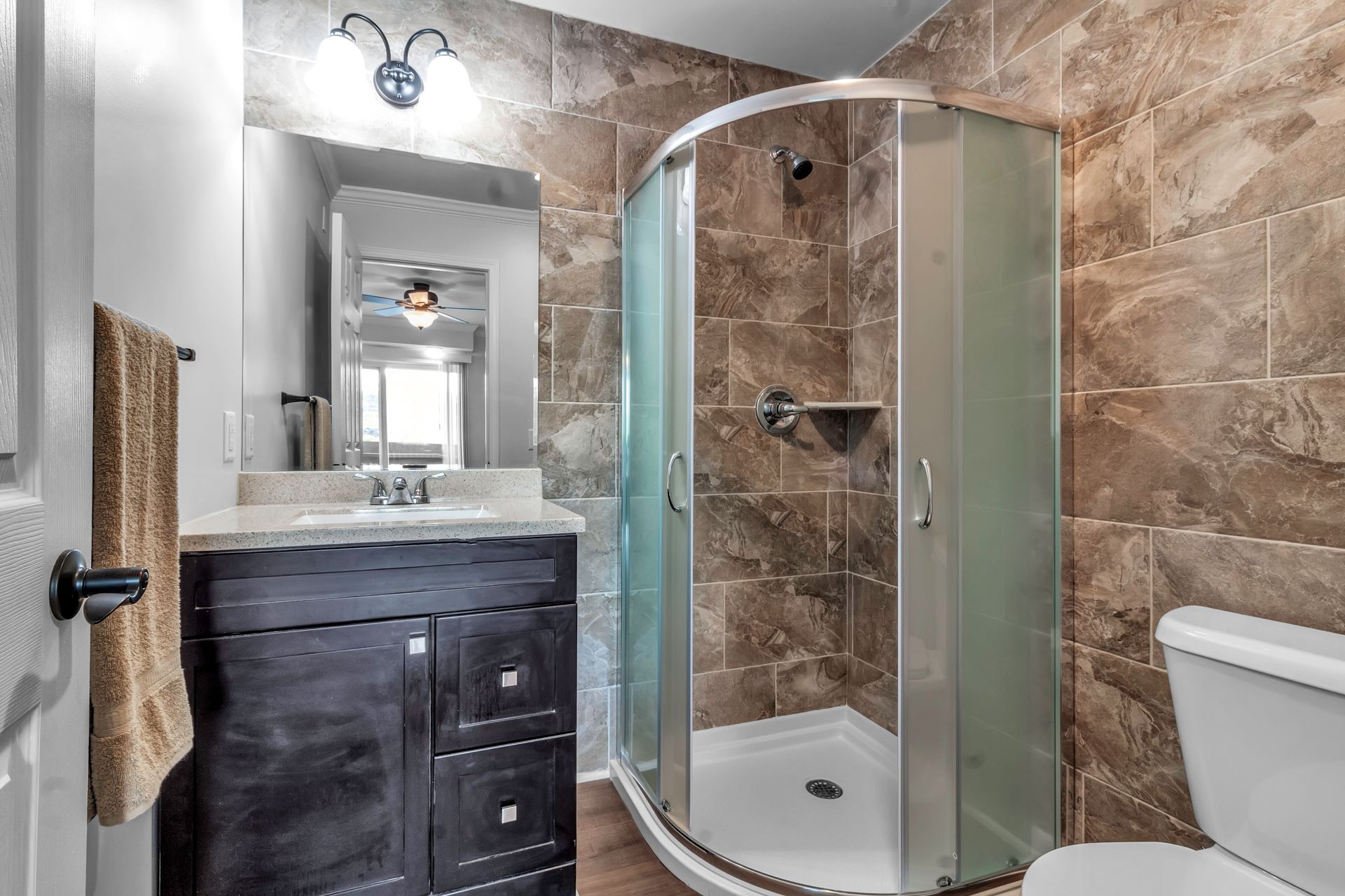 A bathroom with a toilet , sink , shower and mirror.