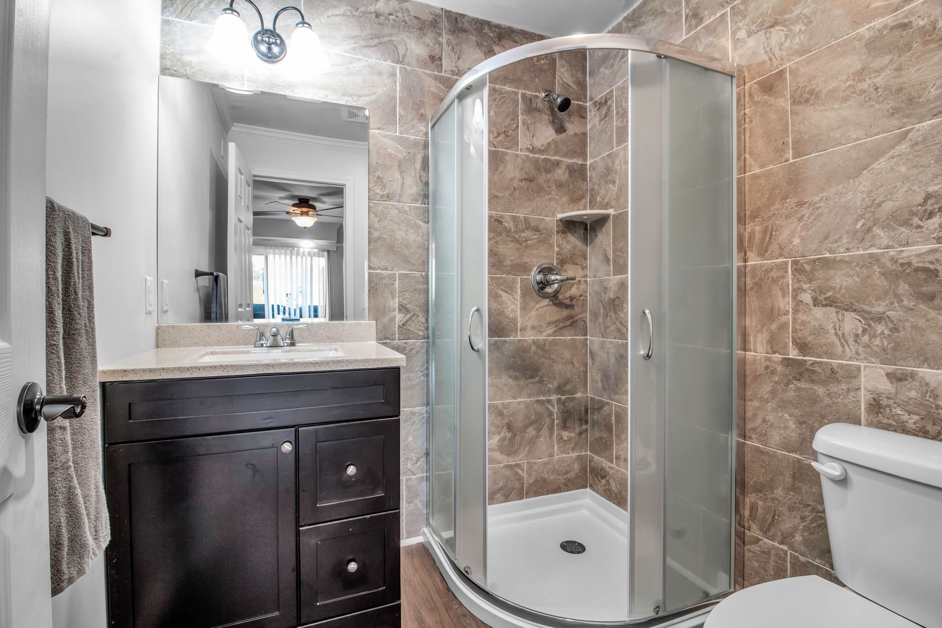 A bathroom with a toilet , sink , shower and mirror.