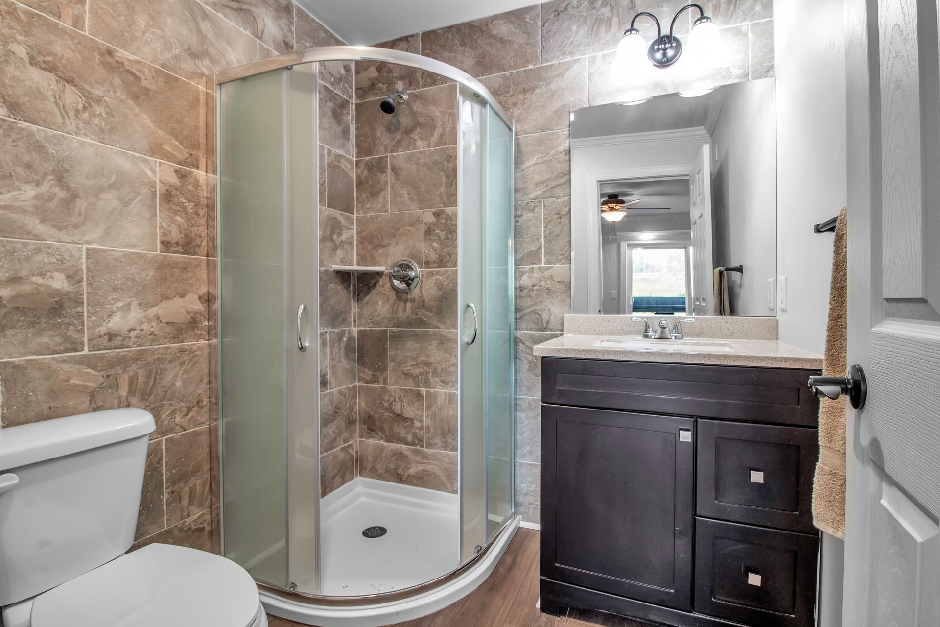 A bathroom with a toilet , sink , shower and mirror.
