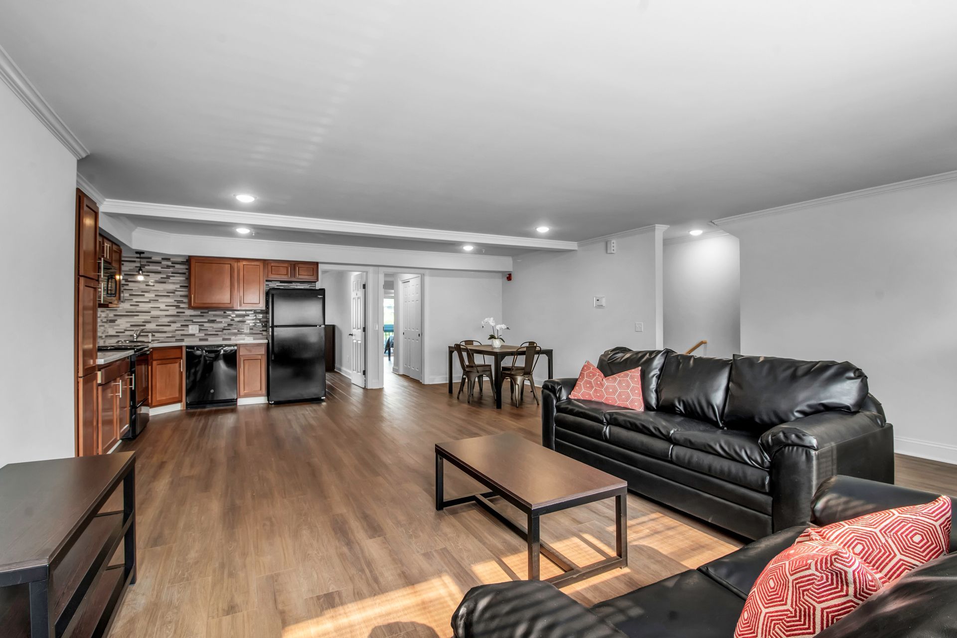 A living room with two couches , a coffee table , and a kitchen.