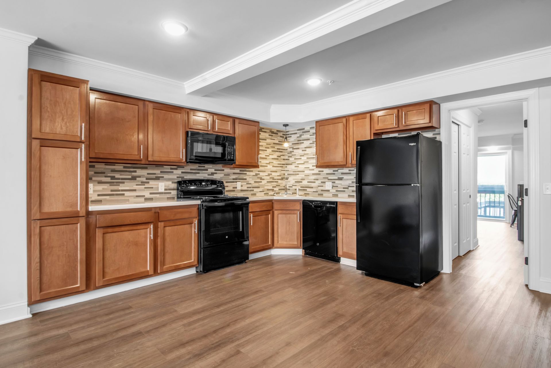 A kitchen with wooden cabinets and a black refrigerator.