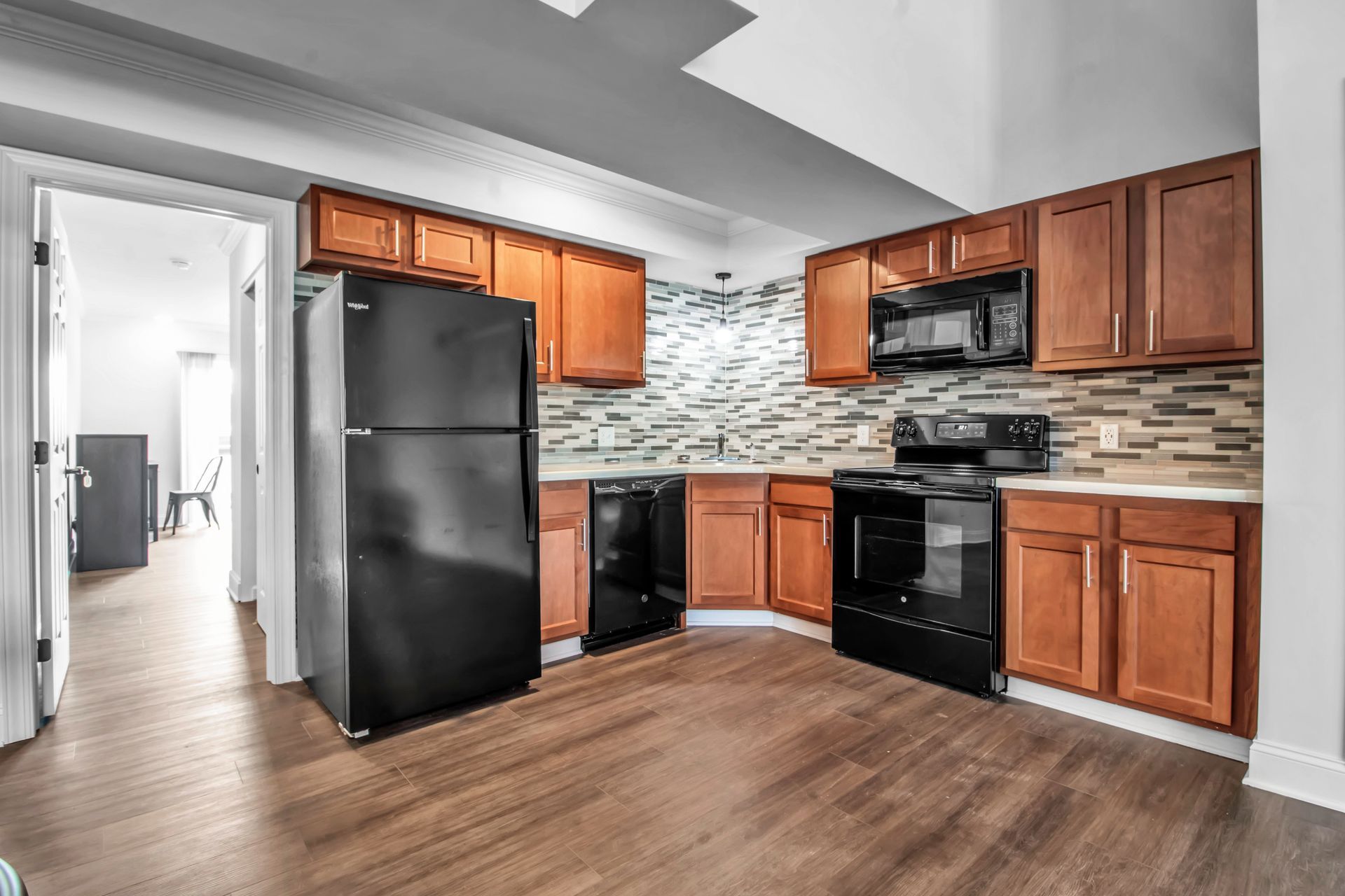 A kitchen with wooden cabinets , a black refrigerator , a stove , and a microwave.