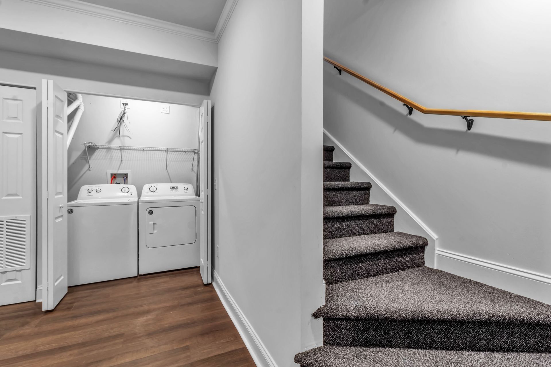 A laundry room with a washer and dryer and stairs leading up to it.
