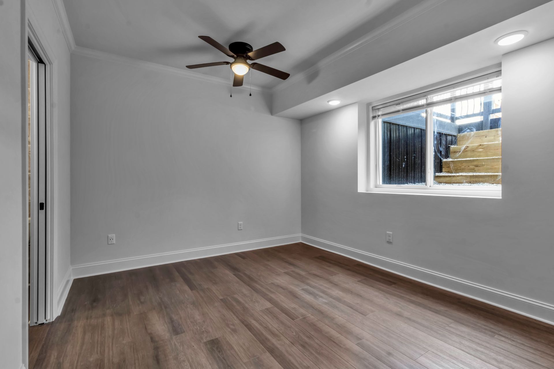 An empty room with a ceiling fan and a window.