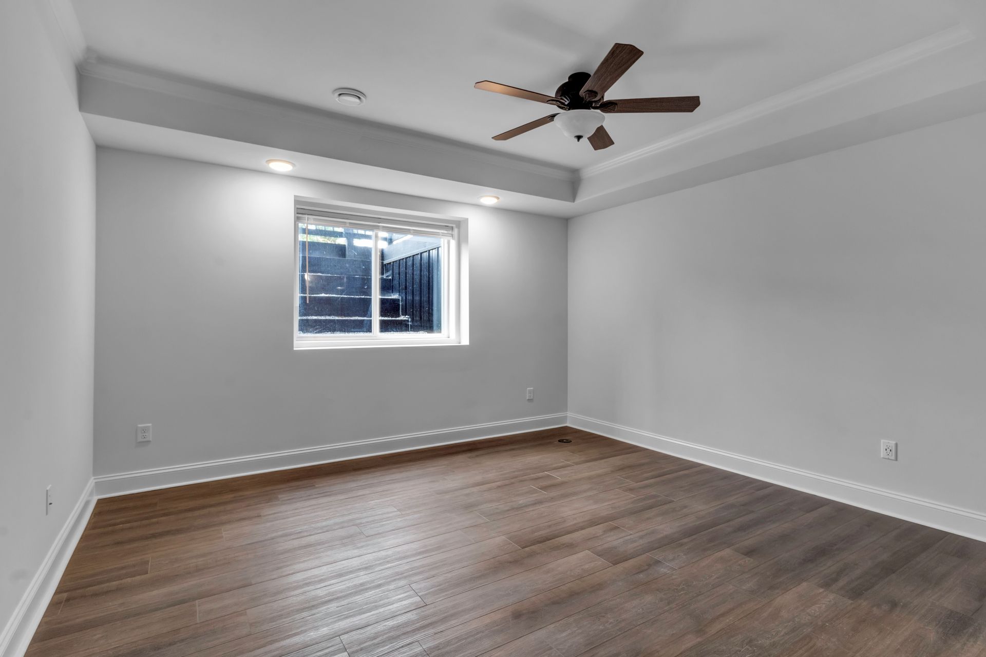 An empty room with a ceiling fan and a window.