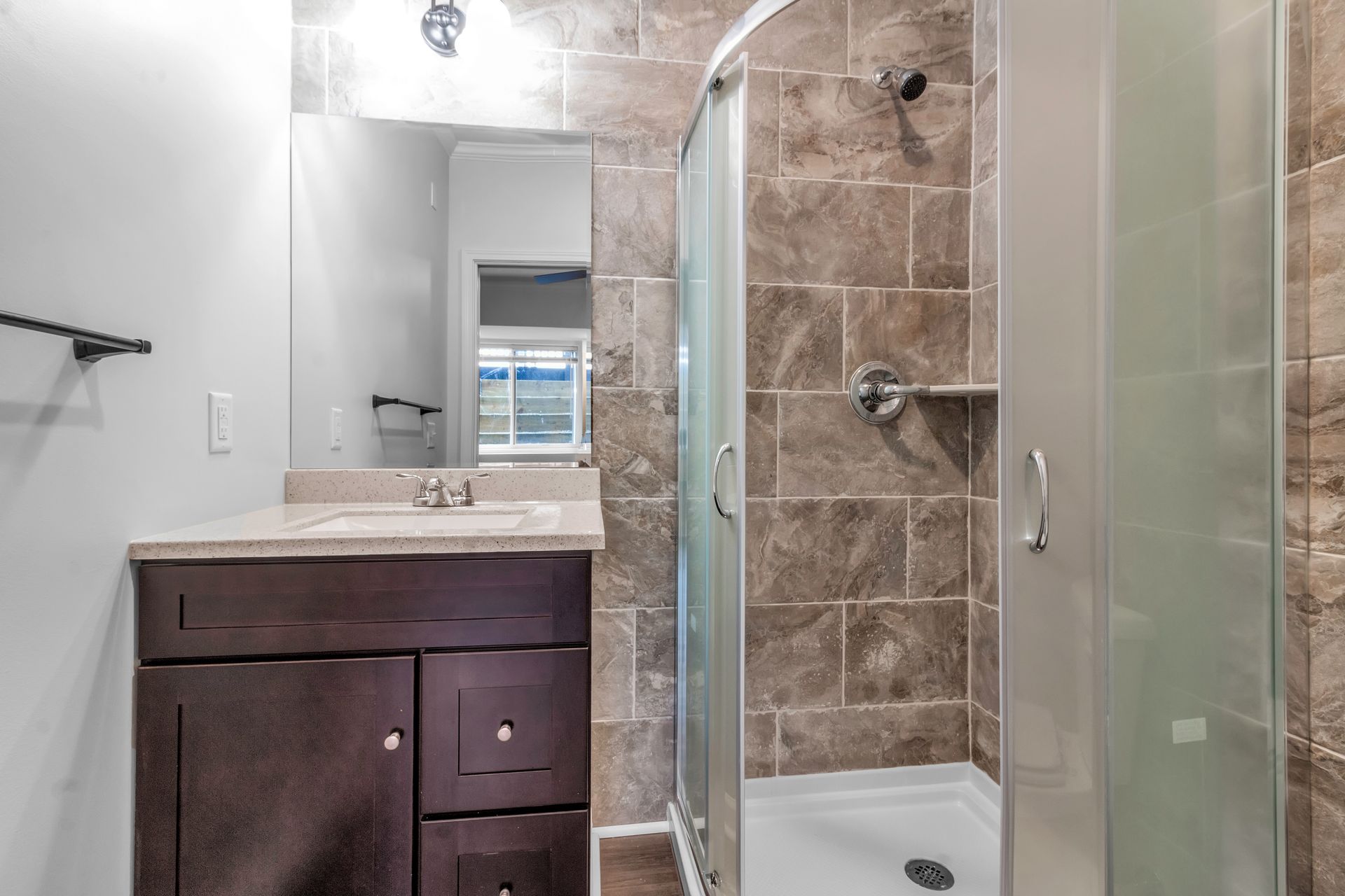 A bathroom with a sink , mirror and walk in shower.