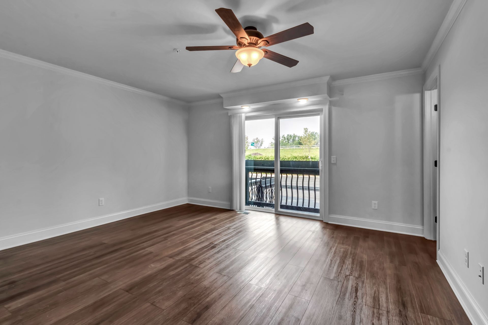 An empty living room with hardwood floors and a ceiling fan.