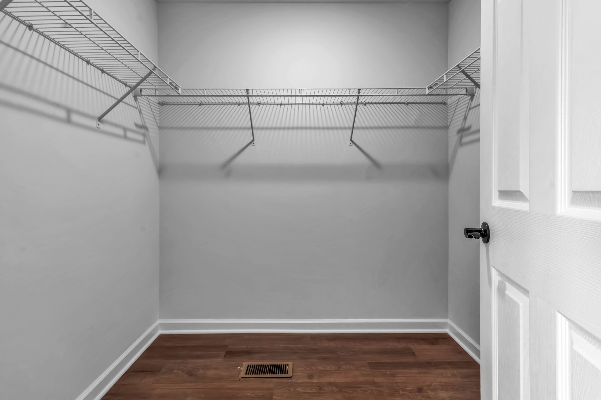 An empty walk in closet with wooden floors and wire shelves.