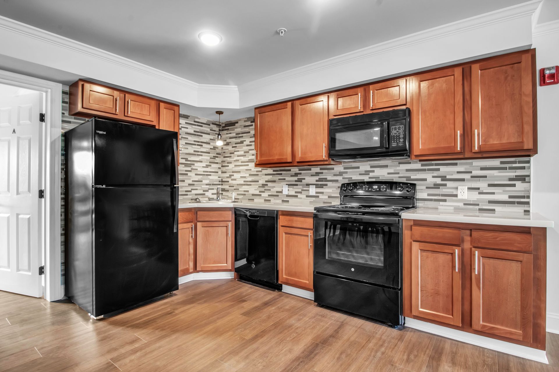 A kitchen with wooden cabinets , black appliances , and a black refrigerator.