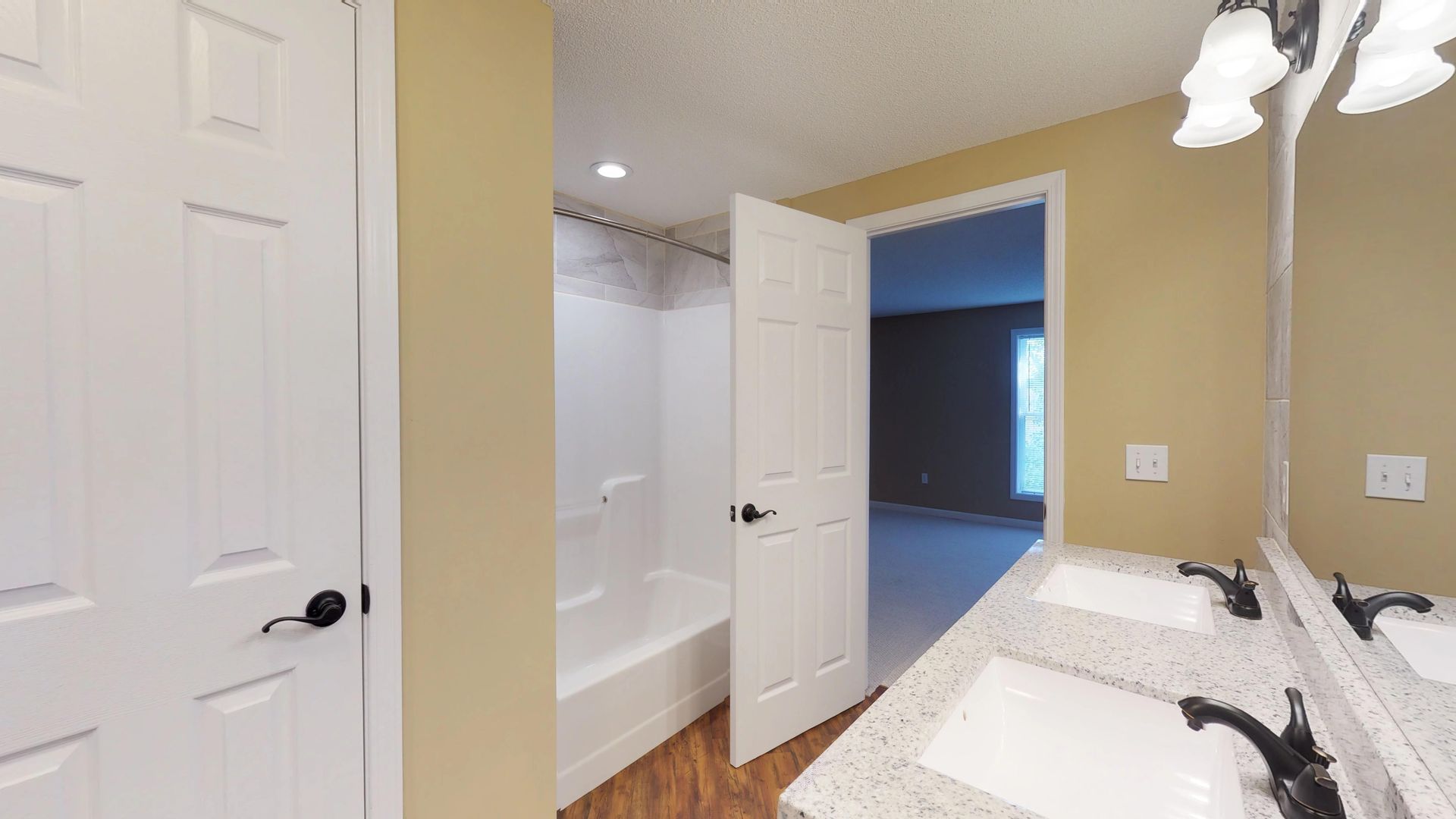 A bathroom with two sinks , a tub and a mirror.