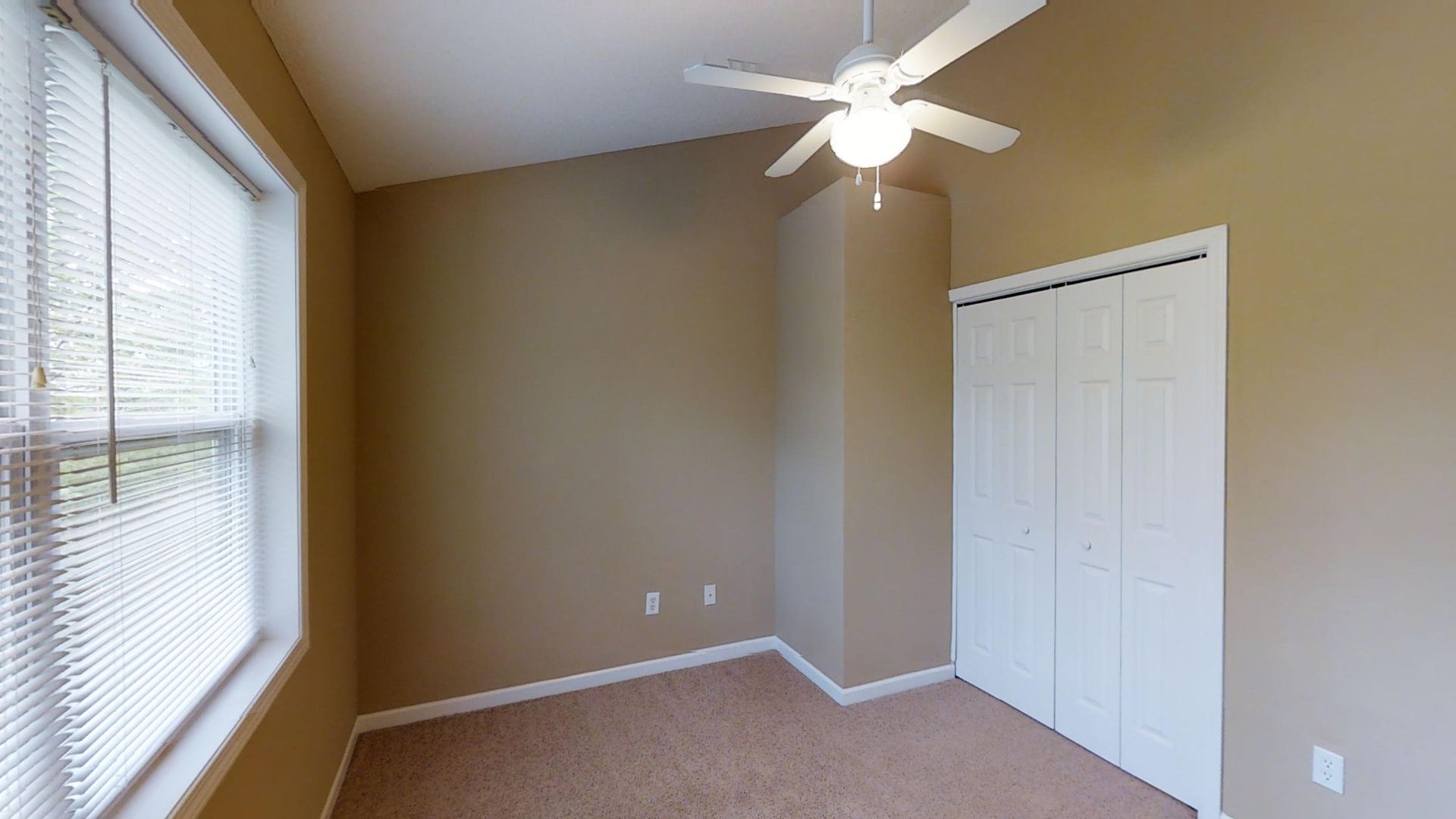 An empty bedroom with a ceiling fan and a window