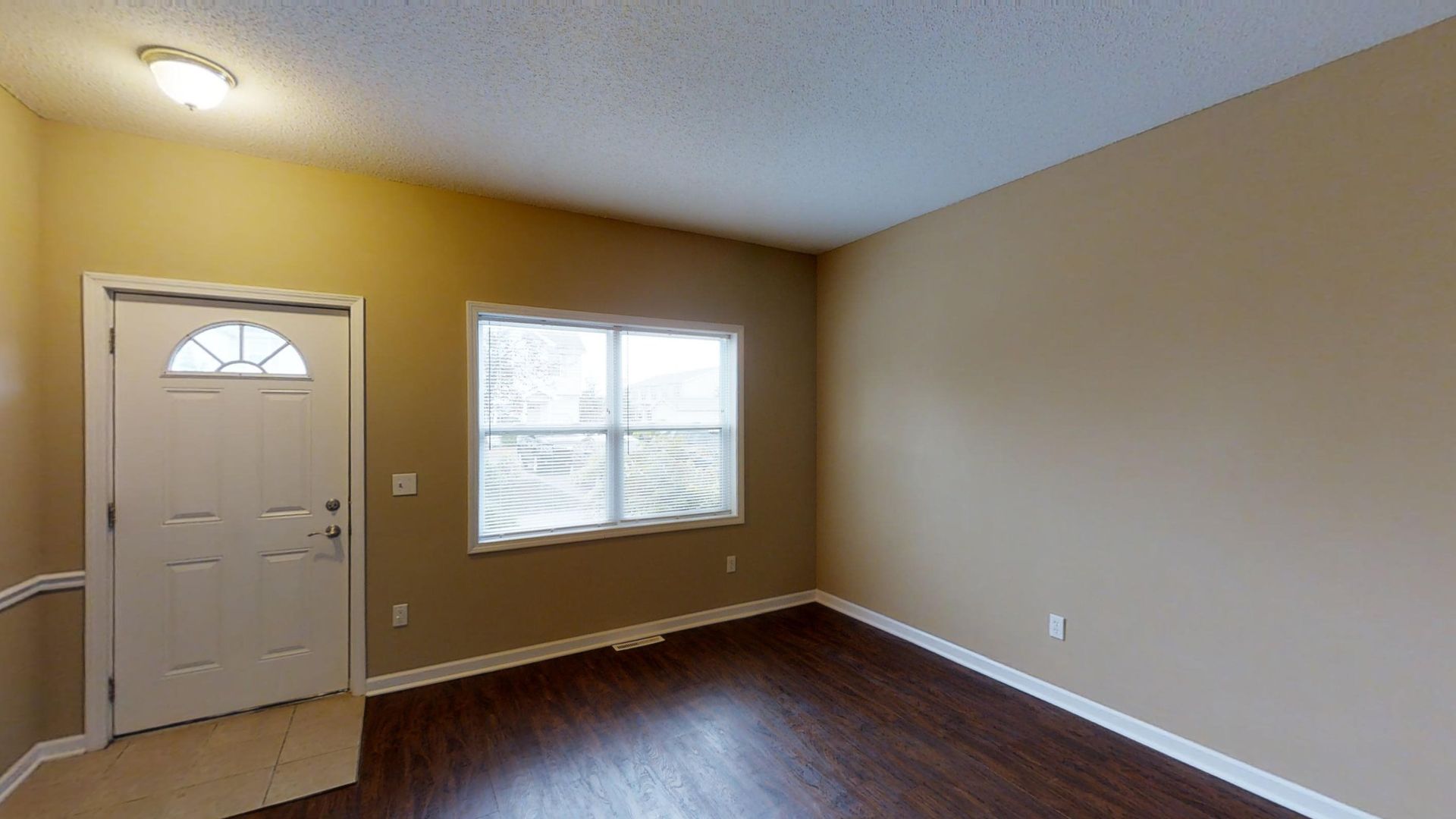 An empty living room with a door and a window.