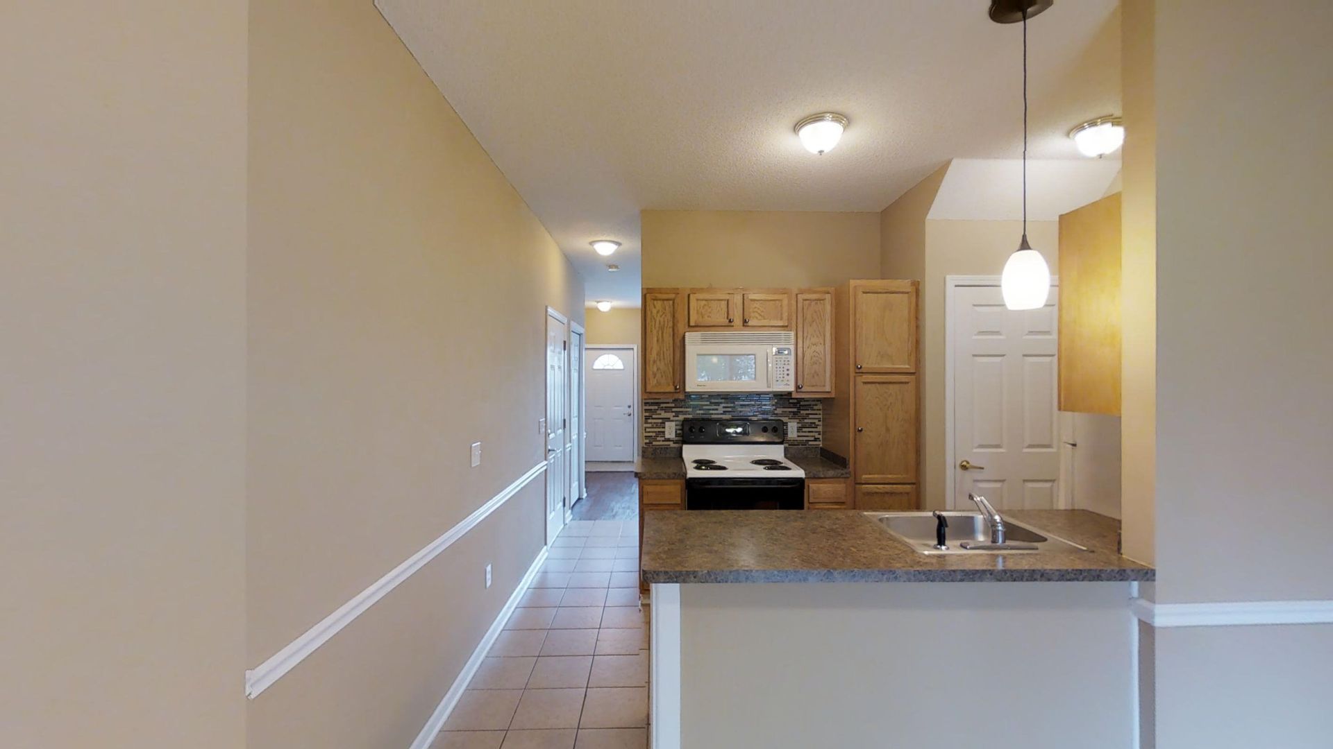 A kitchen with a stove , sink , and cabinets in a house.
