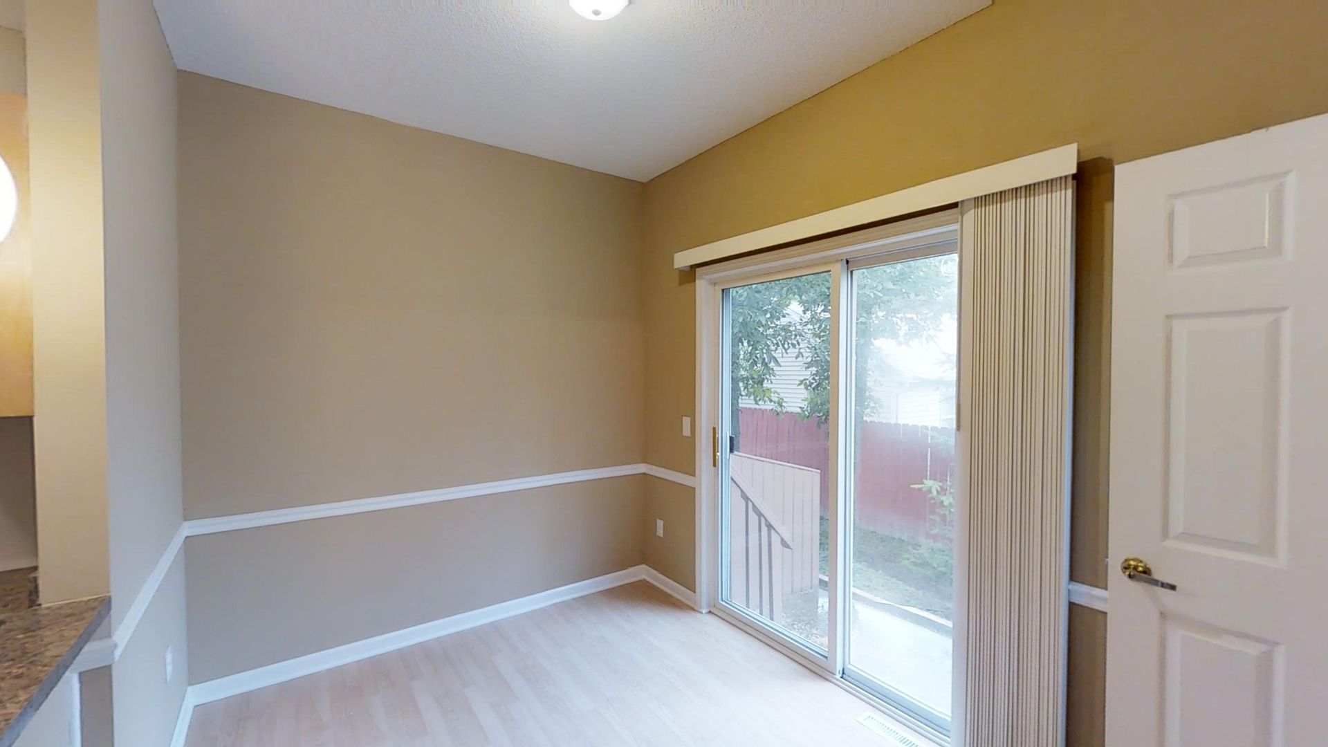 An empty room with a sliding glass door and curtains.