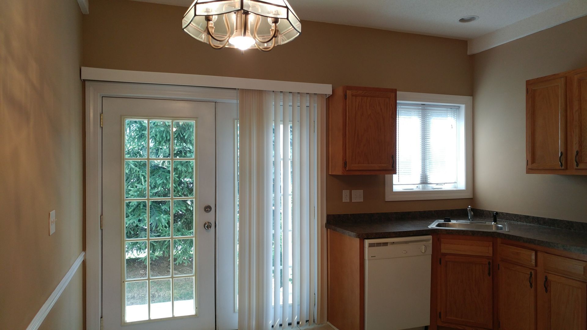 An empty kitchen with wooden cabinets and a sliding glass door