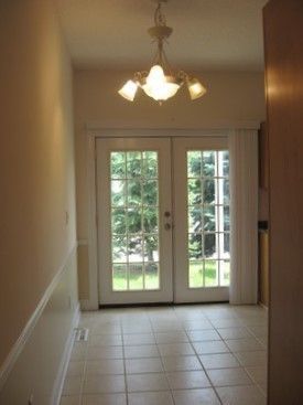 A hallway with french doors and a chandelier hanging from the ceiling