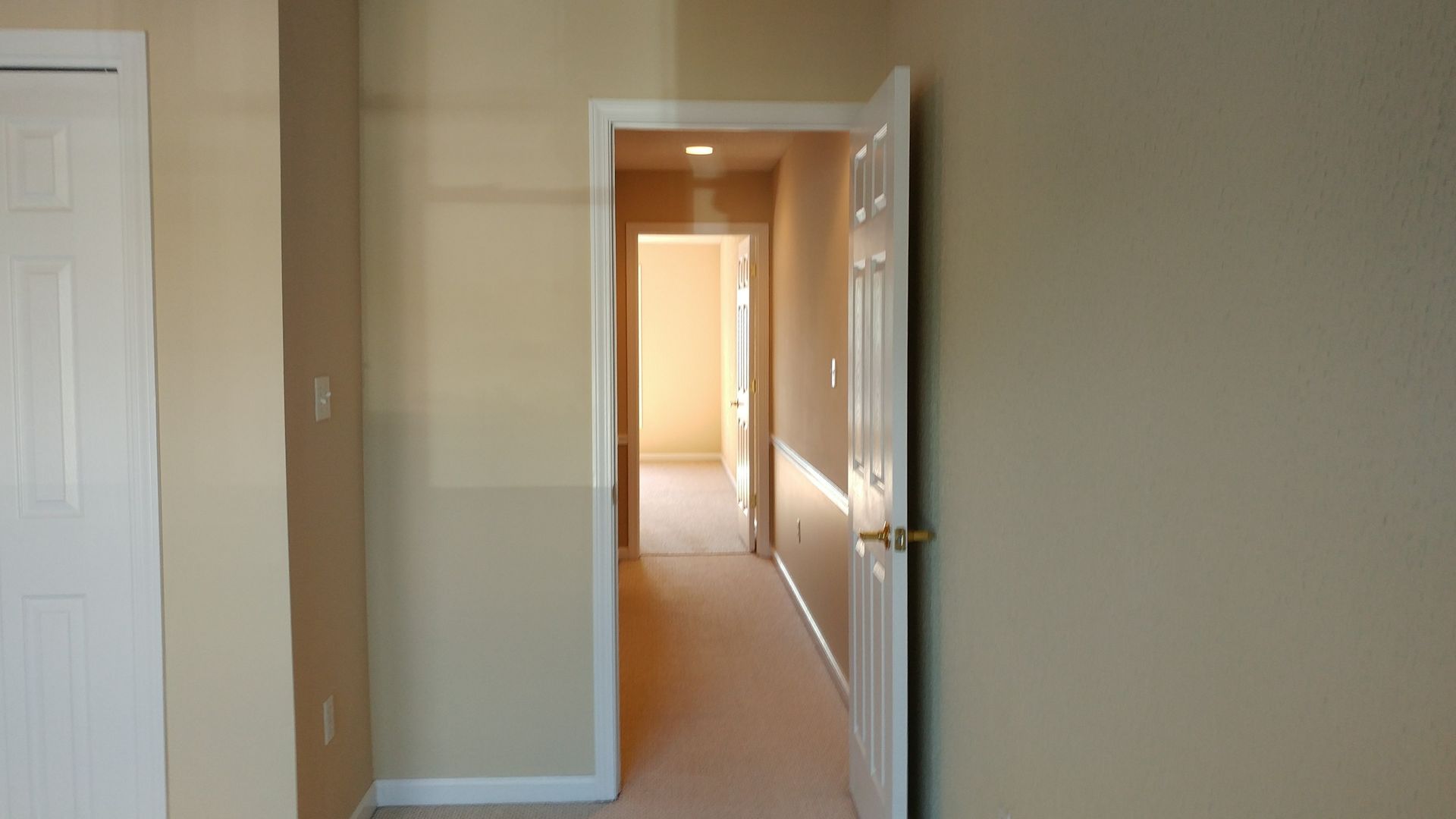 An empty hallway with a door open leading to a bedroom.