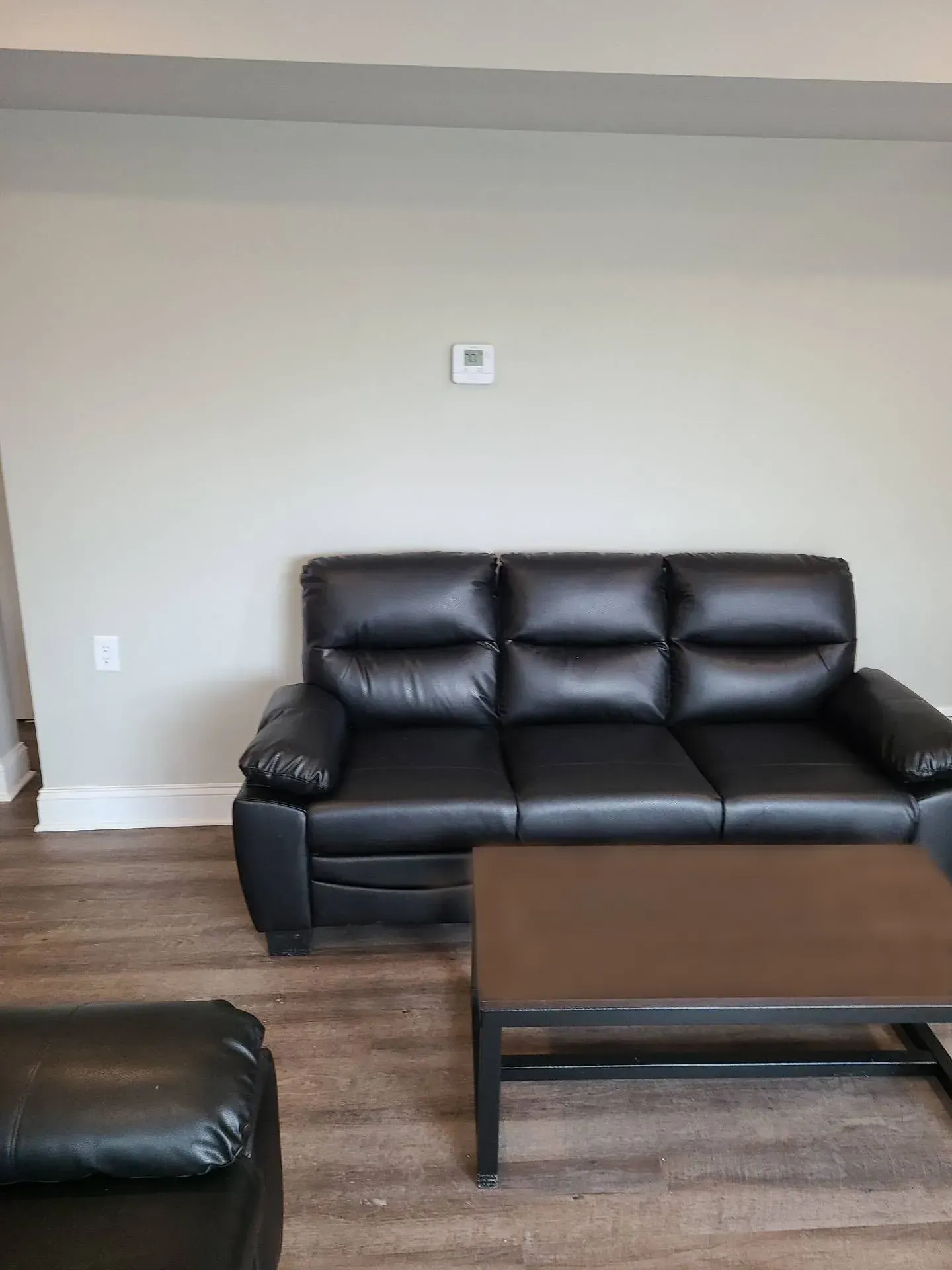 A living room with a black leather couch and a coffee table.