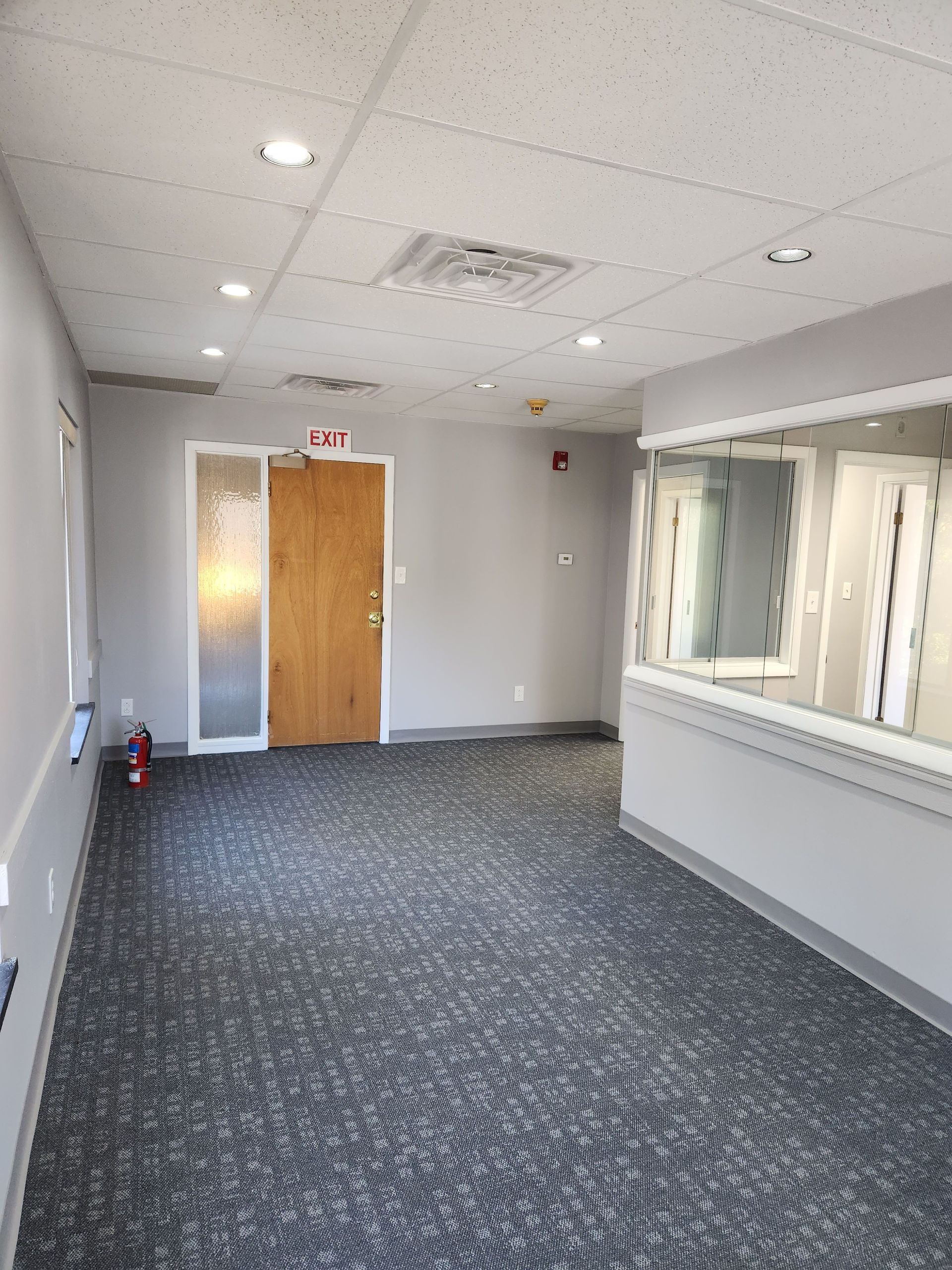 An empty room with a carpeted floor and a wooden door.