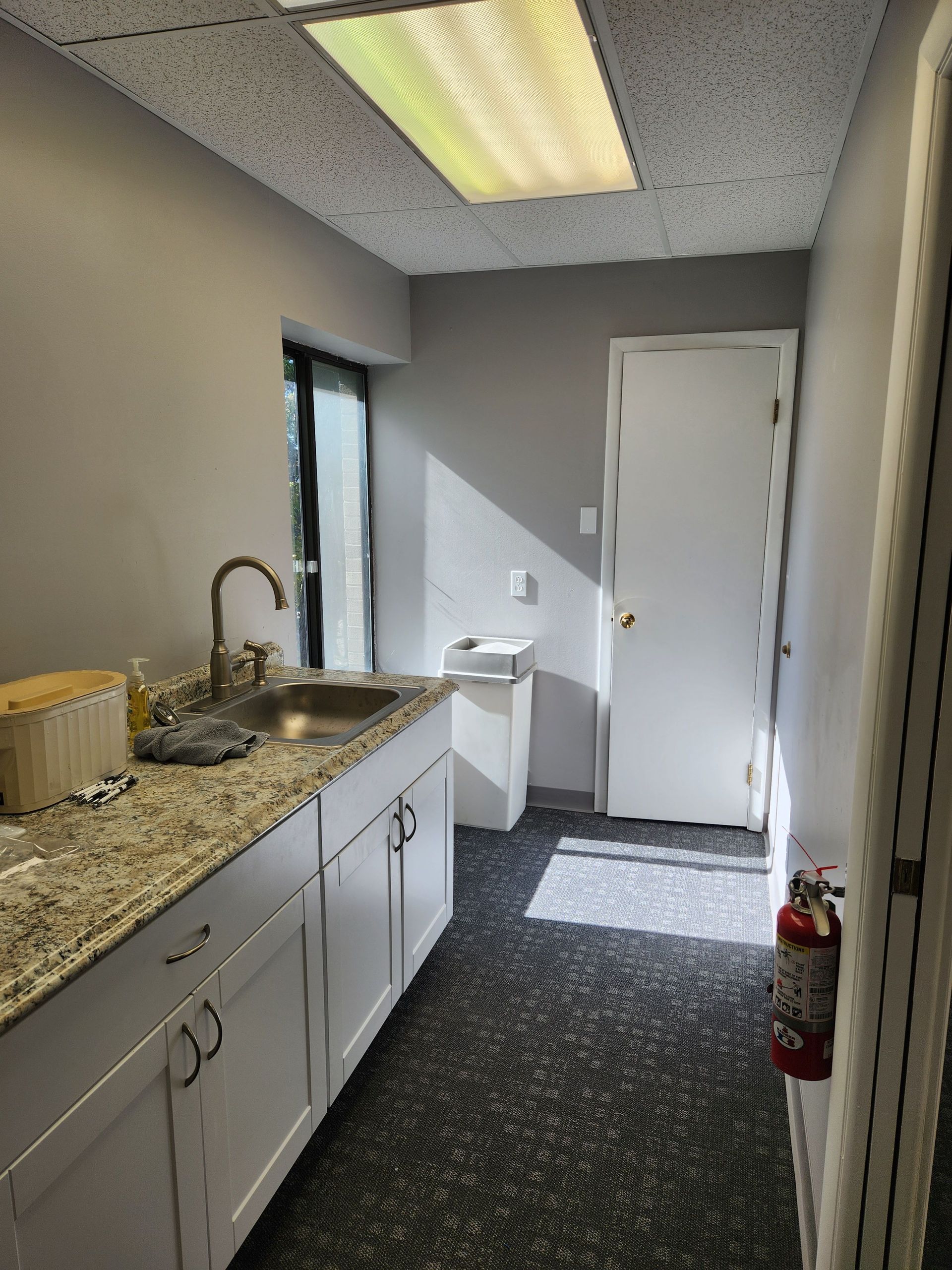 A kitchen with a sink , cabinets , and a fire extinguisher.