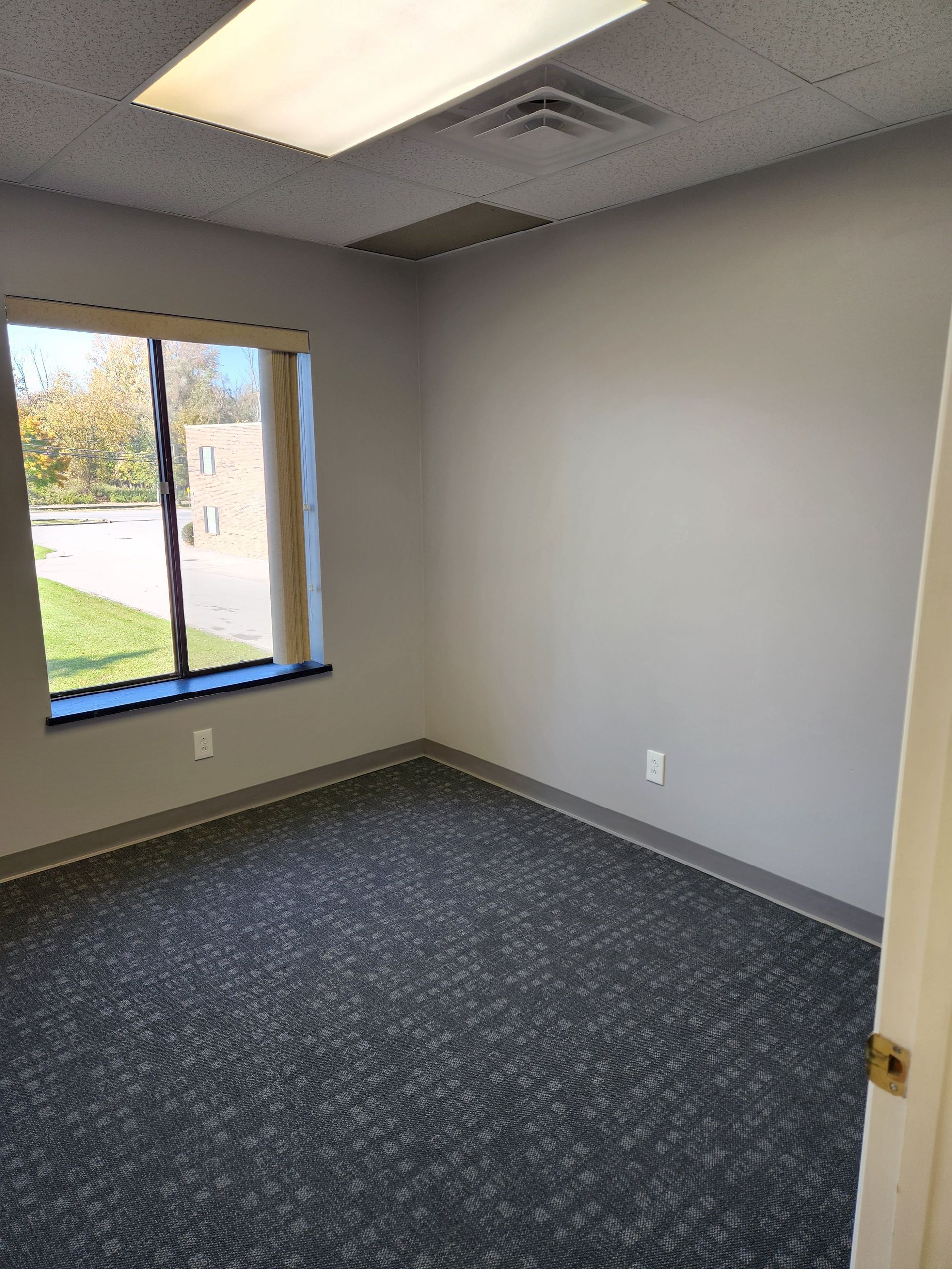 An empty room with a window and a carpeted floor.