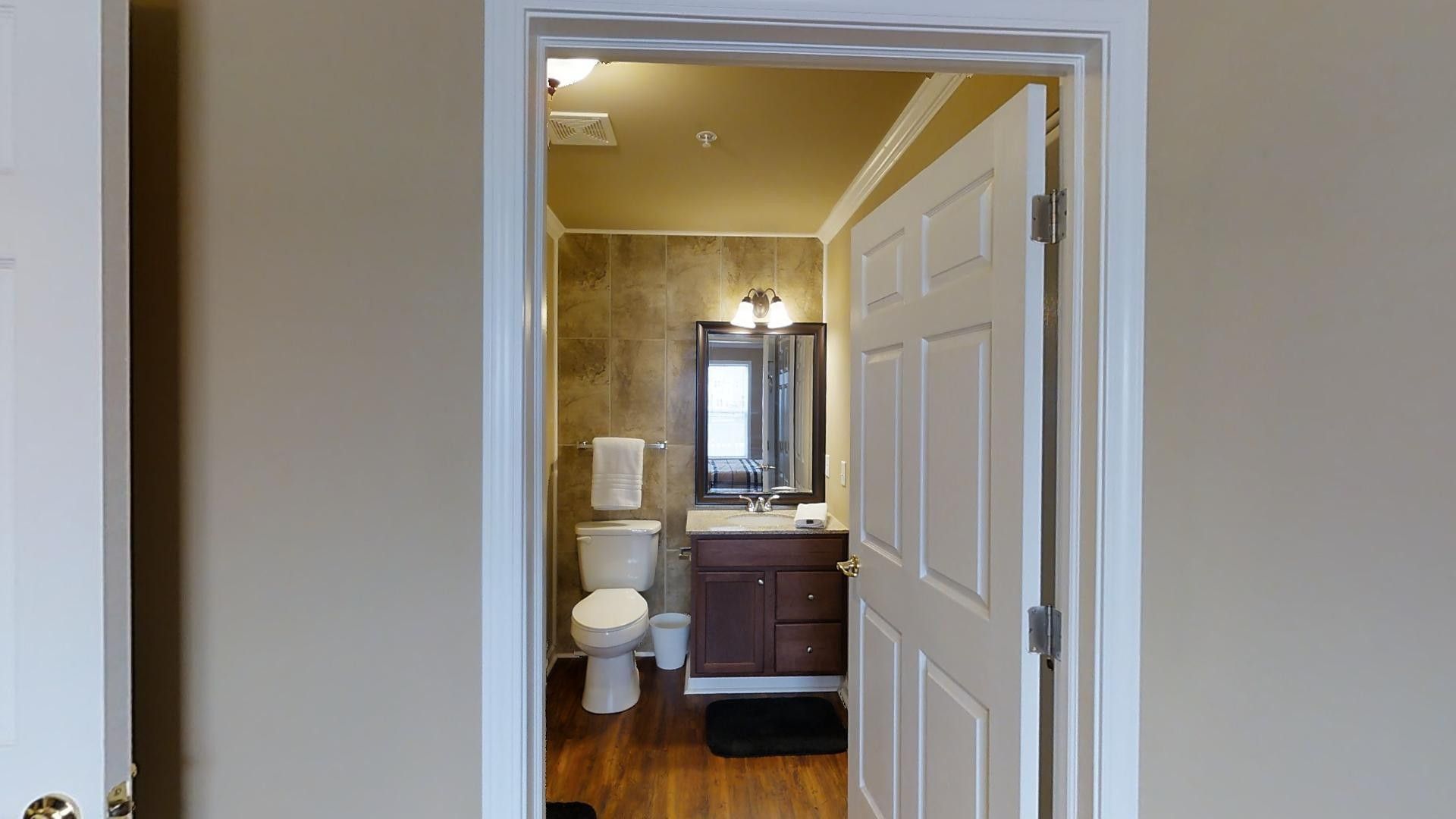 A bathroom with a toilet , sink and mirror.