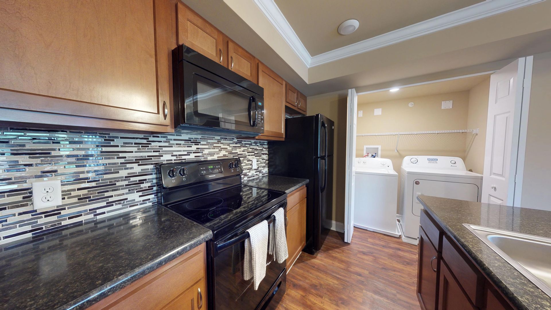 A kitchen with a stove , refrigerator , microwave and sink.