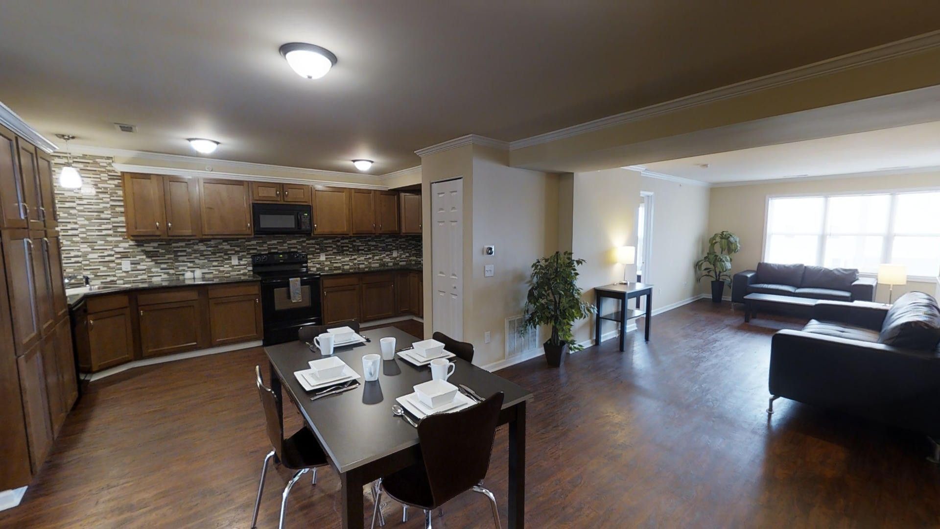 A living room with a dining table and chairs and a kitchen.