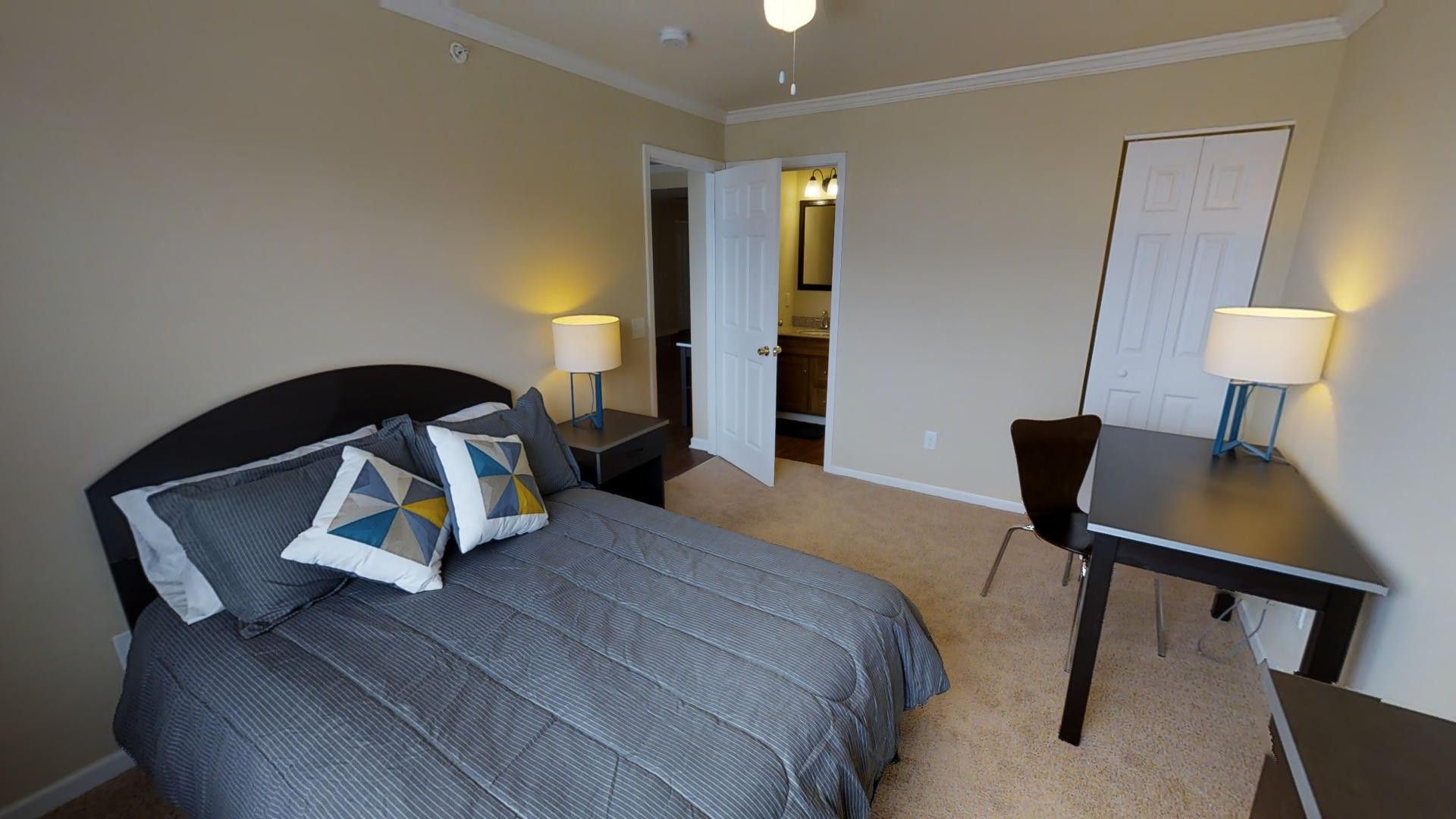 A bedroom with a bed , desk and lamps