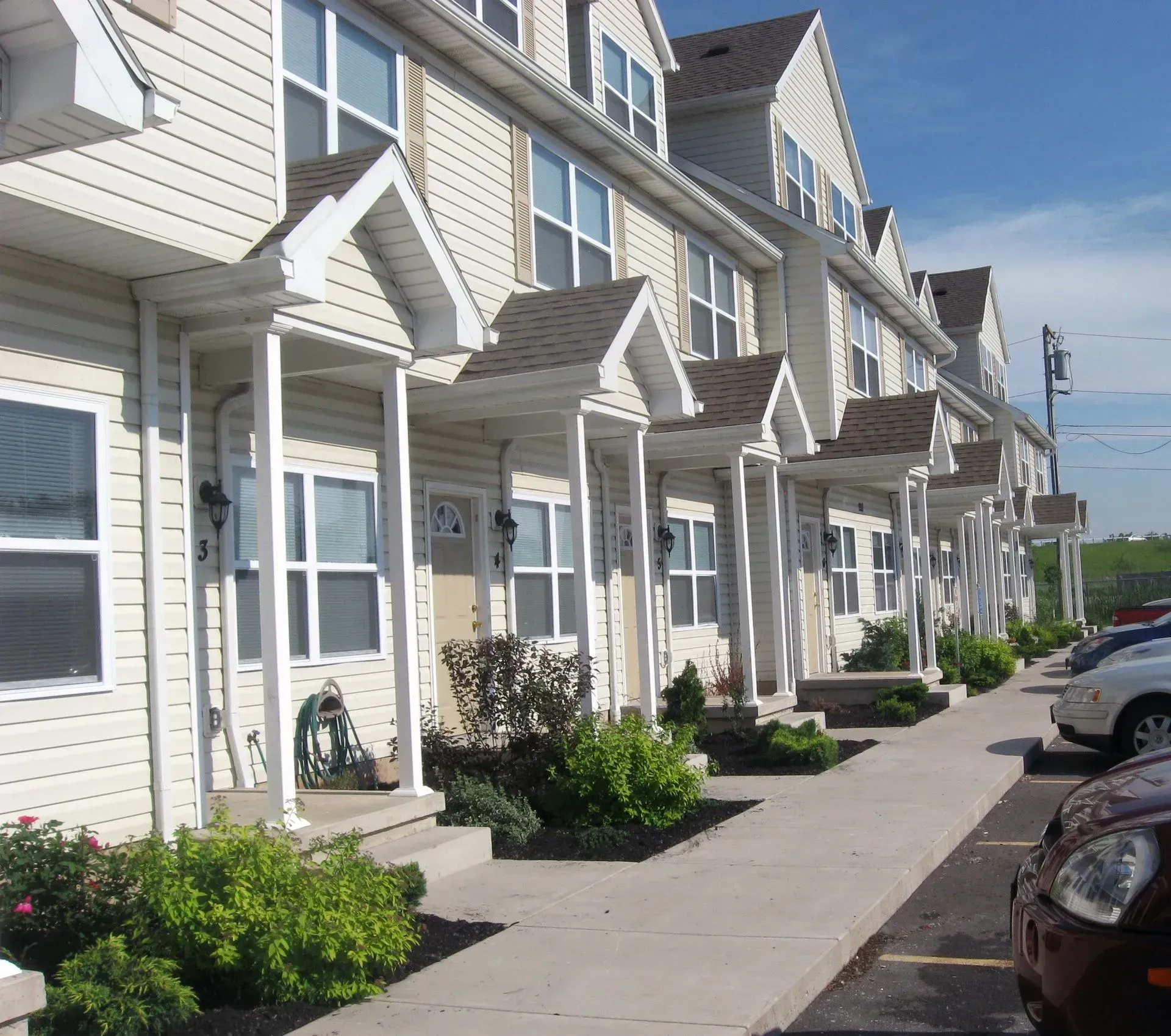 A row of houses with cars parked in front of them