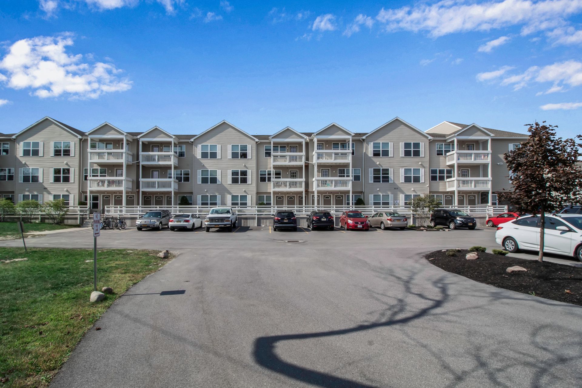 A large apartment building with cars parked in front of it.