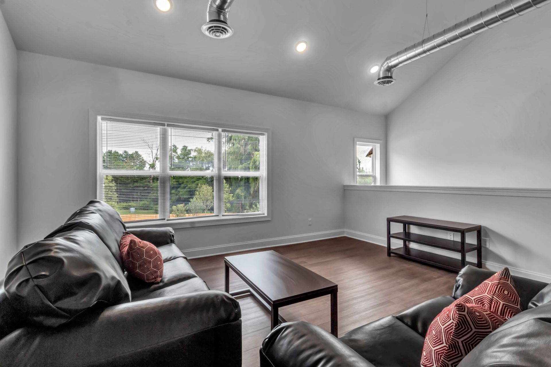 A living room with two couches , a coffee table , and two windows.