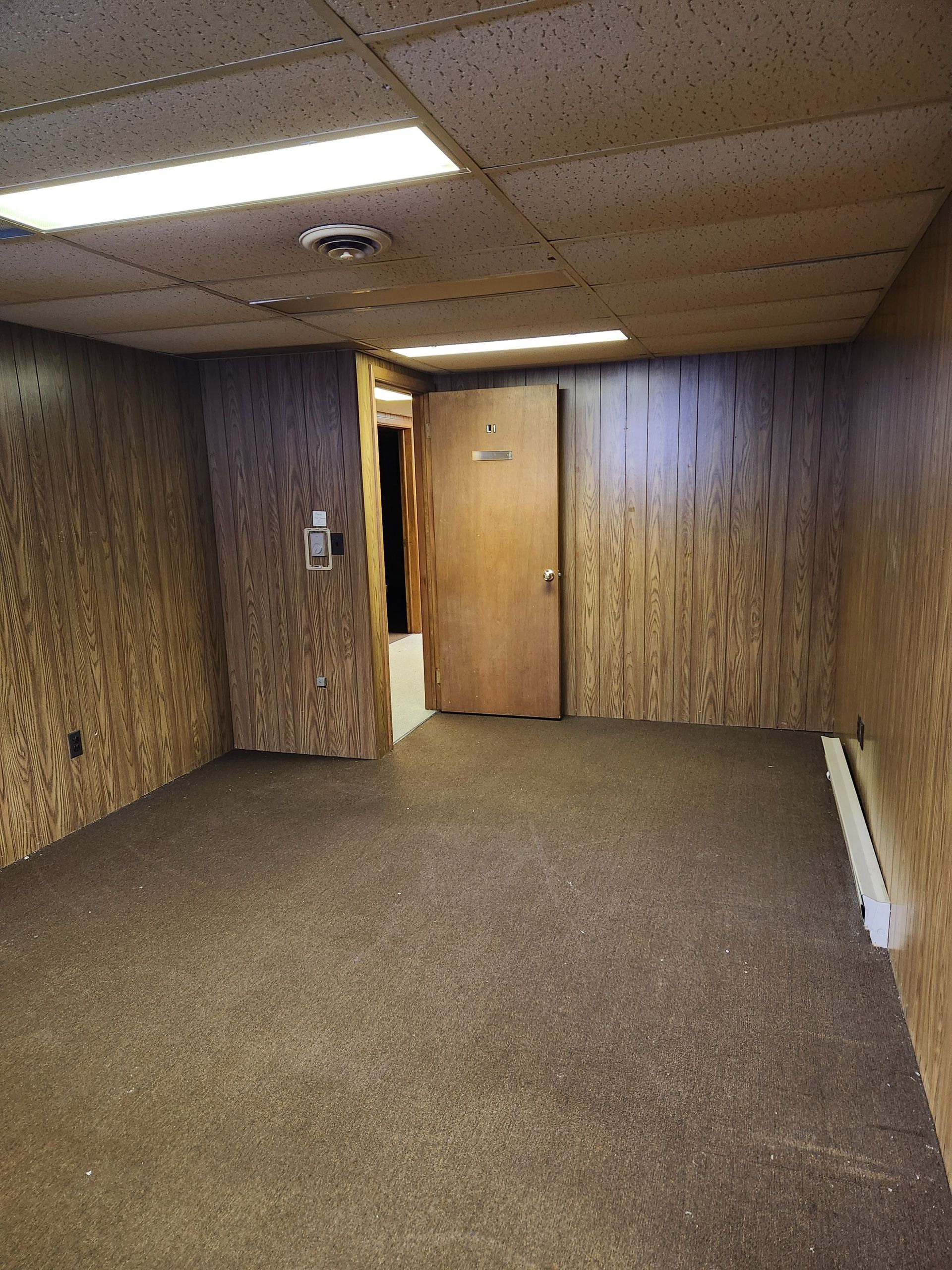 An empty room with a door and a carpeted floor