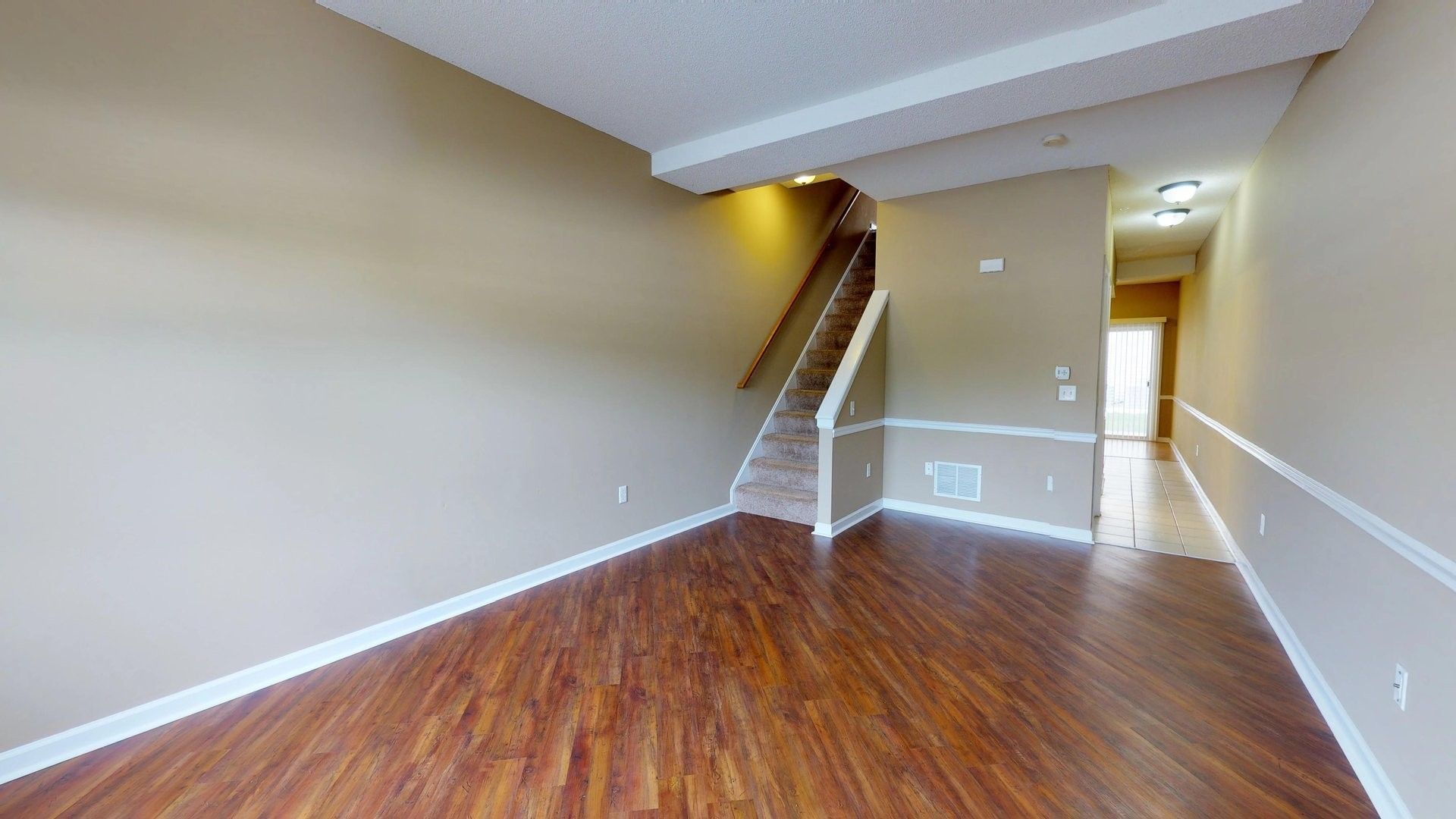 An empty living room with hardwood floors and stairs.