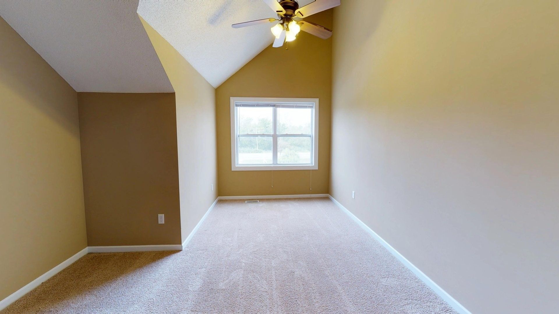 An empty room with a ceiling fan and a window