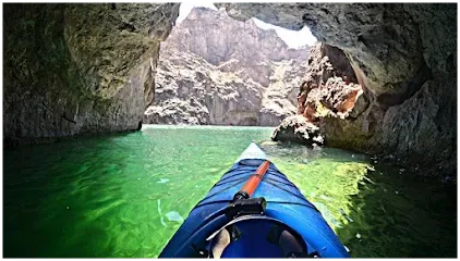 A person is riding a kayak through a cave in the water.
