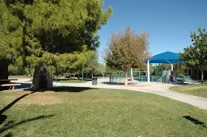 A park with a blue umbrella and a playground in the background