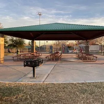 A picnic shelter with tables and a grill in a park.