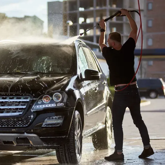Mobile Detailing Sin City - A man in a black shirt is washing a black suv