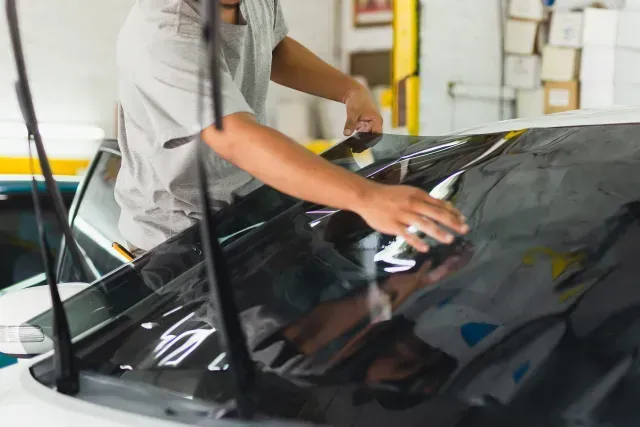 Mobile Detailing Sin City - a man is applying tinted glass to a car window .