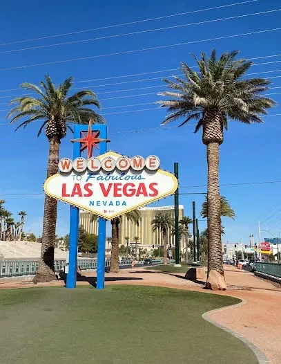 A welcome to las vegas sign with palm trees in the background