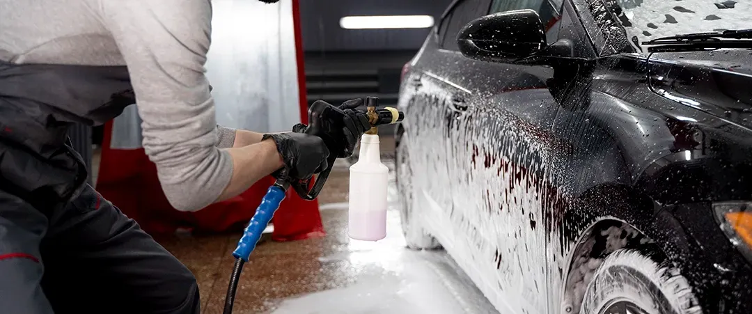 A man is washing a car with foam in a car wash.
