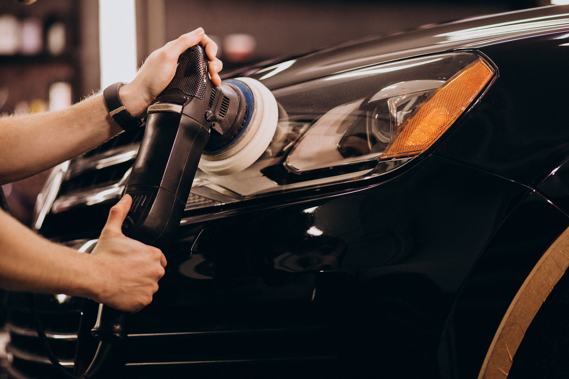 a man is polishing the headlight of a black car .