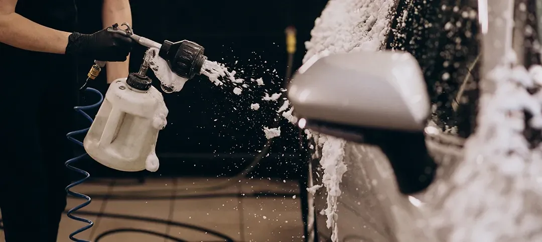 A woman is washing a car with a spray bottle.