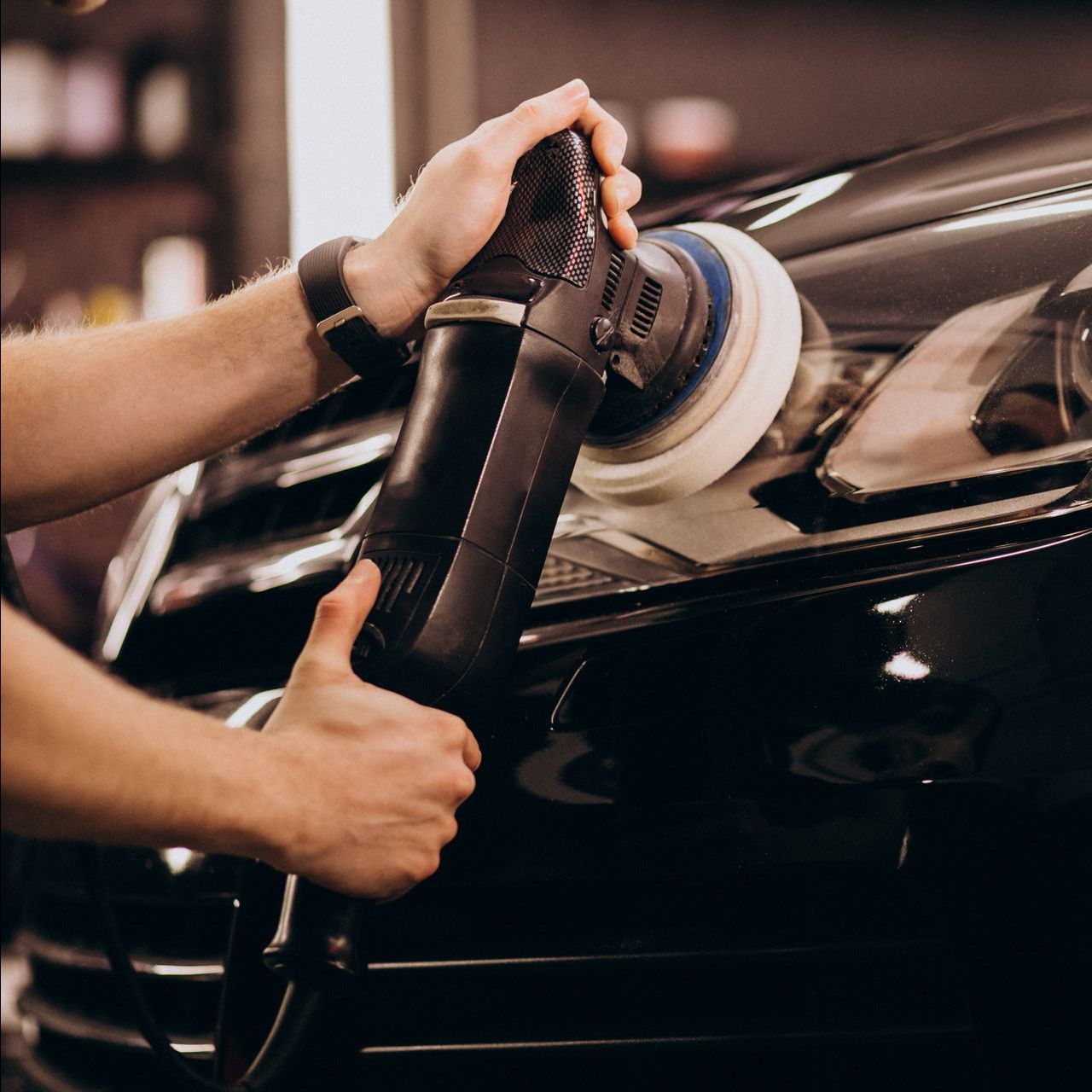 a man is polishing the headlight of a black car .